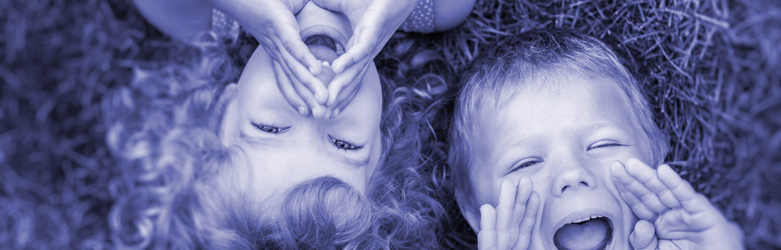 looking down a boy and girl lying on grass  taking to the camera